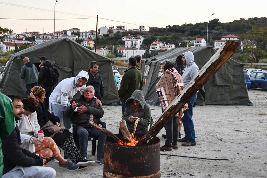 Locals sit around a fire near tents after an earthquake.