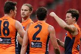 GWS Giants AFL players in a huddle as they celebrate a goal against Geelong.