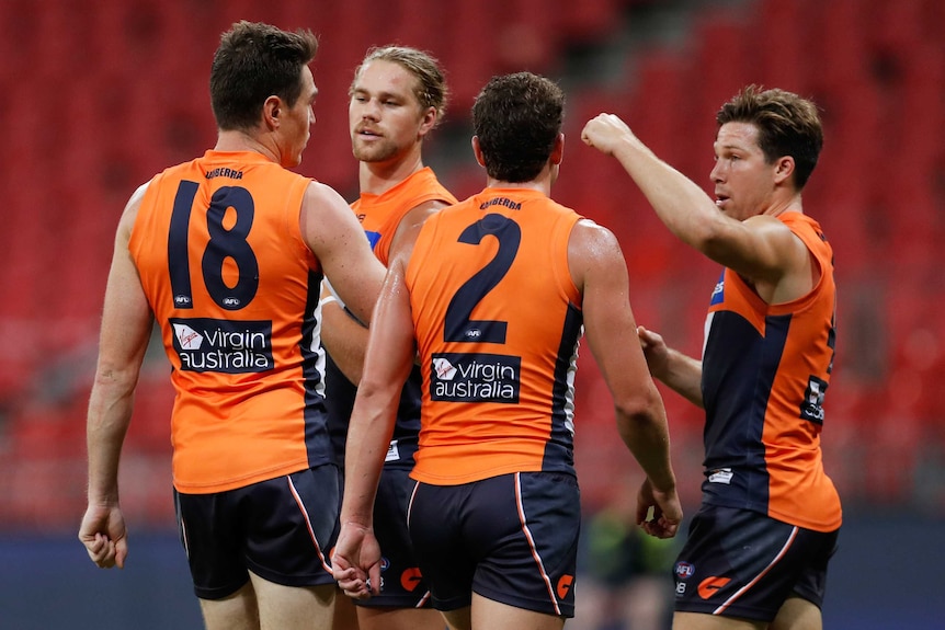 GWS Giants AFL players in a huddle as they celebrate a goal against Geelong.