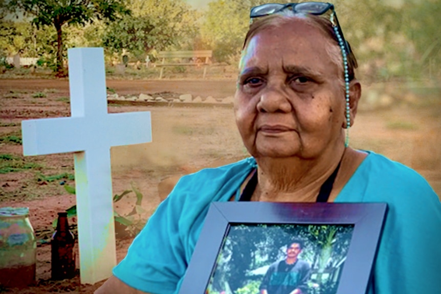 A woman in a blue short holding a photograph of a young Aboriginal man