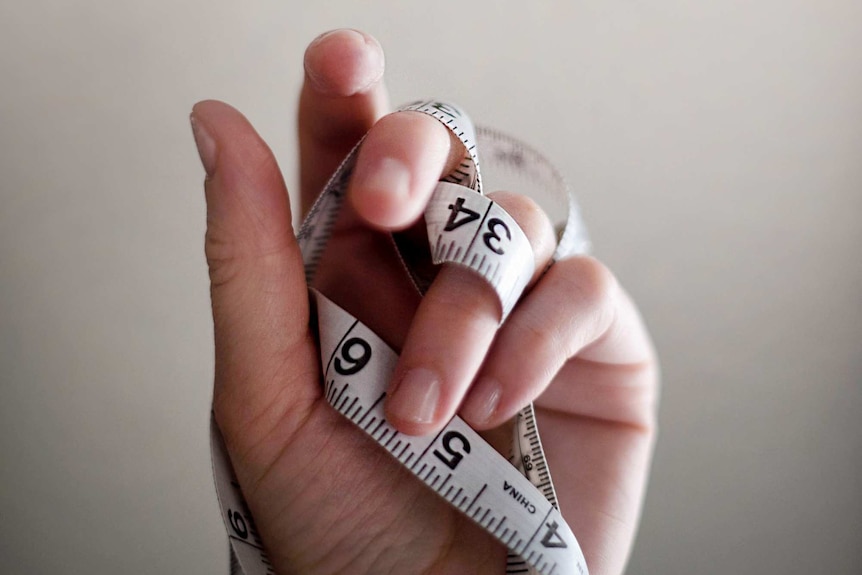 A hand holds a tangled tape measure.