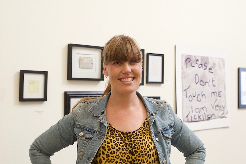 Medium portrait shot of a woman standing in an art gallery smiling at the camera.