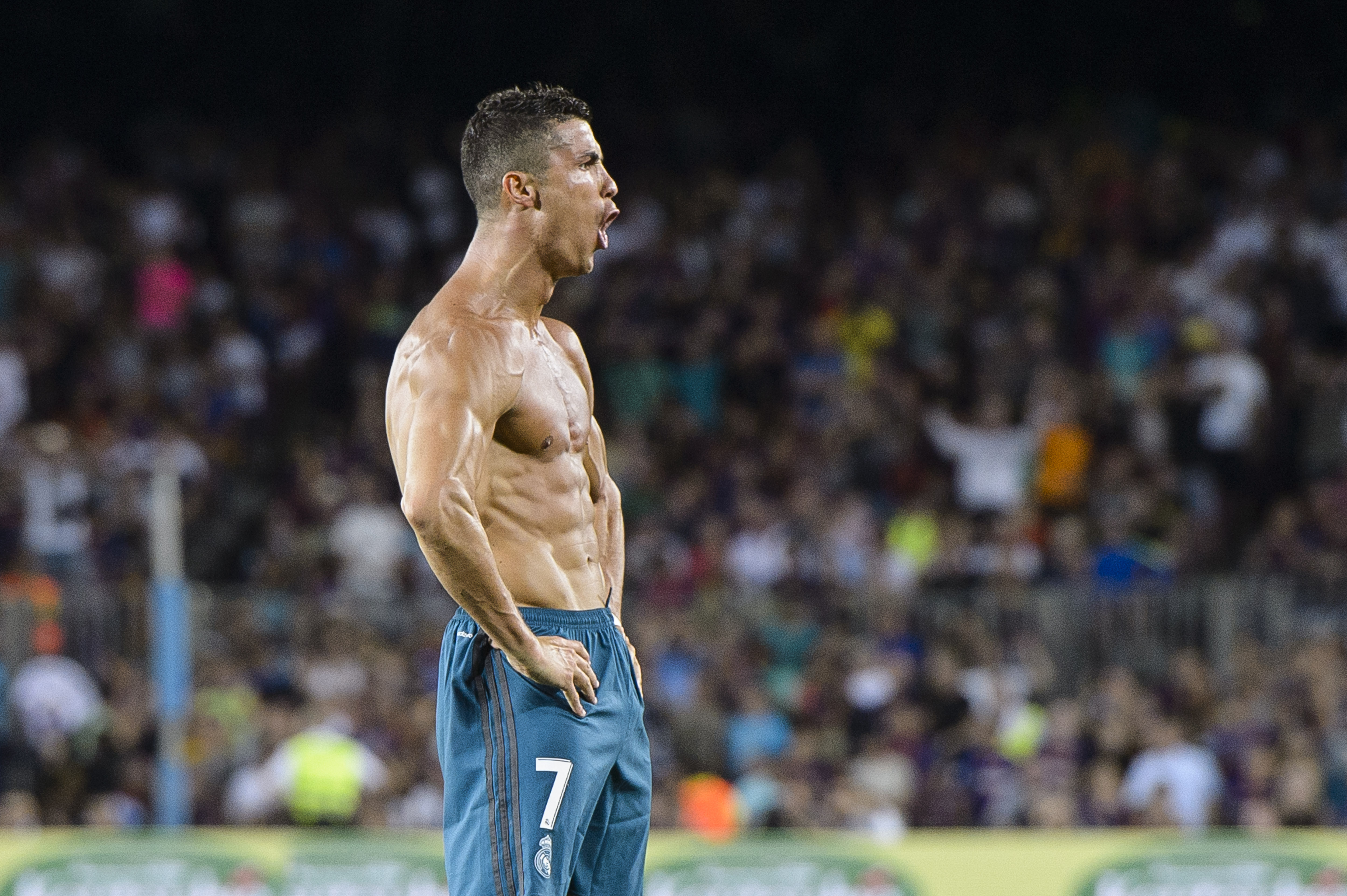 Cristiano Ronaldo has his shirt off and has his hands on hip, screaming to celebrate