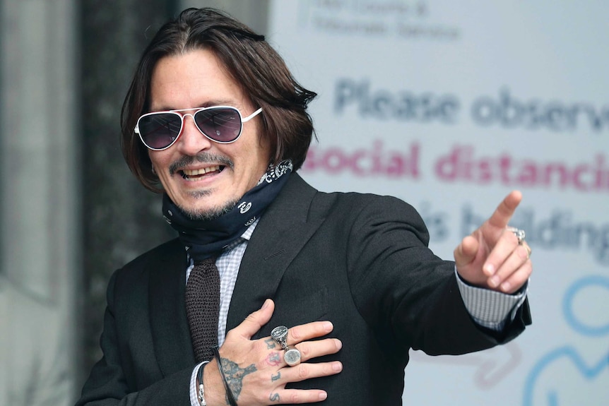 Actor Johnny Depp smiles and gestures as he arrives at the High Court to give evidence in his libel case.