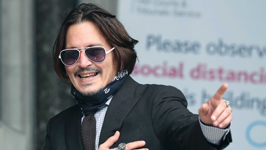 Actor Johnny Depp smiles and gestures as he arrives at the High Court to give evidence in his libel case.