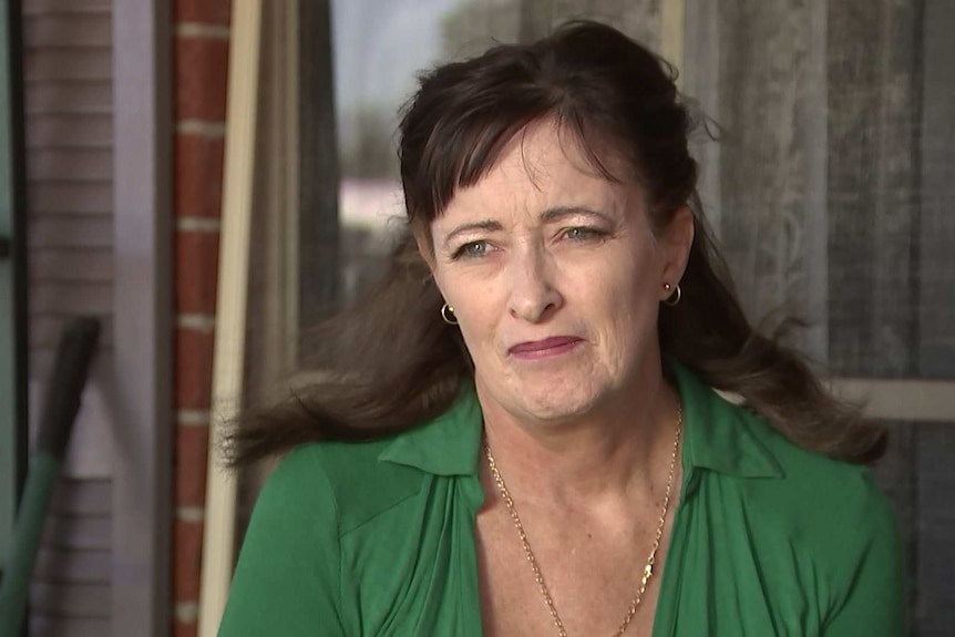 A woman in a green top with dark hair looking concerned.