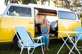 Hayley Donaldson sit in the open door of her yellow Volkswagon Kombi at a Van Life gathering in northern NSW