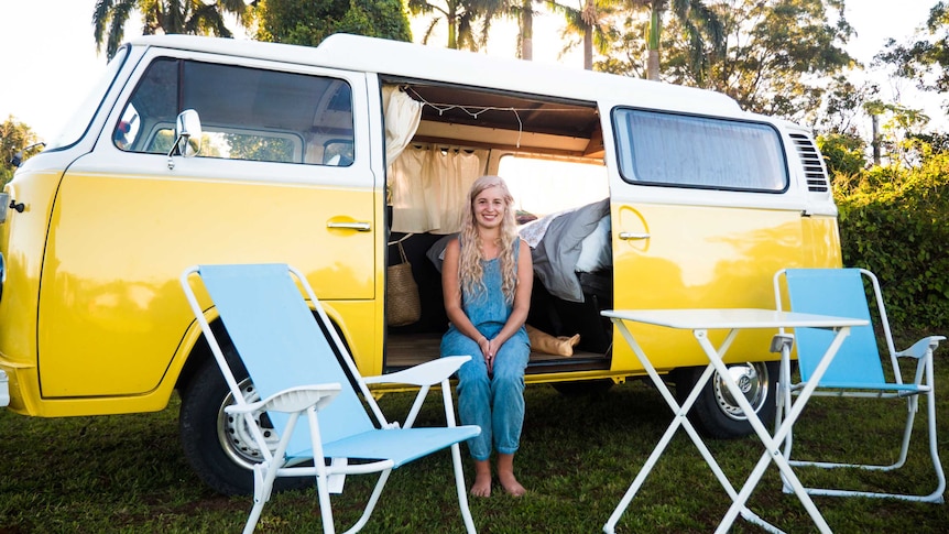 Hayley Donaldson sit in the open door of her yellow Volkswagon Kombi at a Van Life gathering in northern NSW