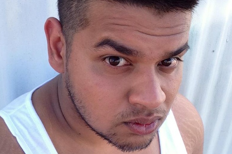 A young man takes a selfie in a white singlet