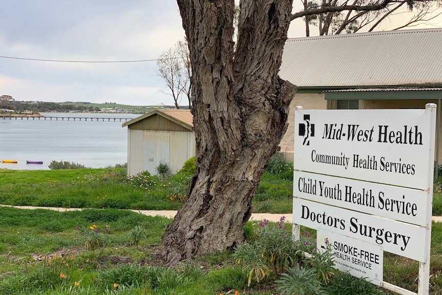 A photo of the Streaky Bay medical clinic sign with the sea in the background.