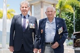 Korean War veterans Walter Raleigh and Ron Walker stand in front of Cairns' cenotaph surrounded by palm trees