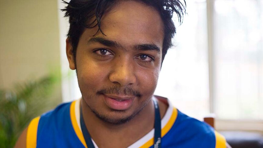 Young Indigenous man looks at the camera in a close up portrait.