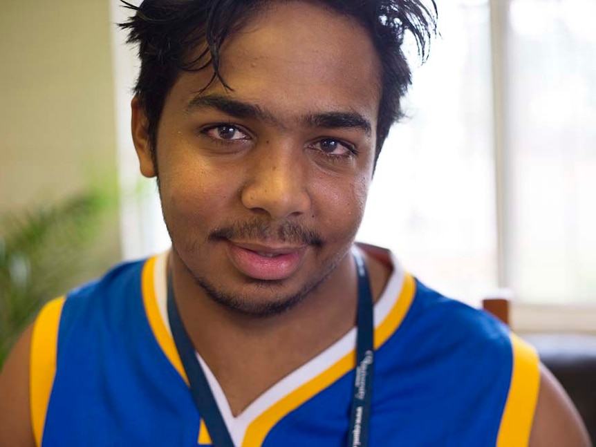 Young Indigenous man looks at the camera in a close up portrait.