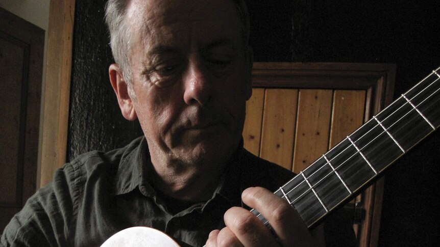A close up picture of Luka Bloom holding an acoustic guitar