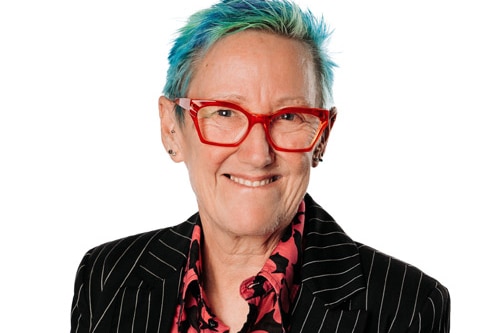 A person with red glasses and dyed blue, green hair. 