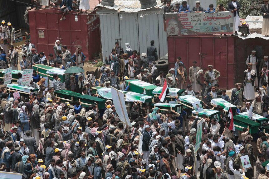 Yemeni people carry the coffins of victims