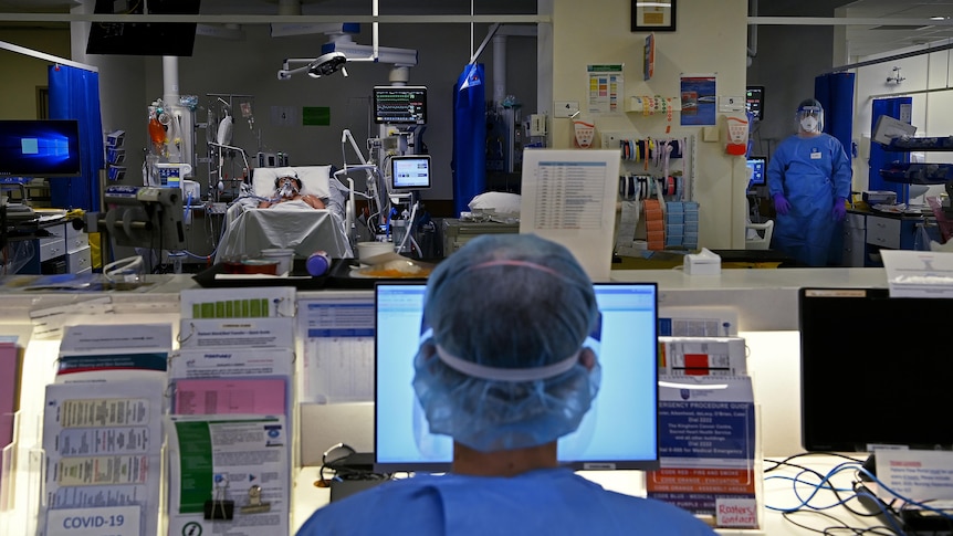 medical staff wearing protective clothing in a ward caring for a patient