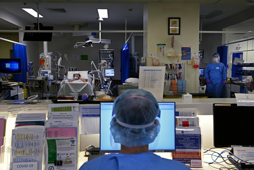 medical staff wearing protective clothing in a ward caring for a patient