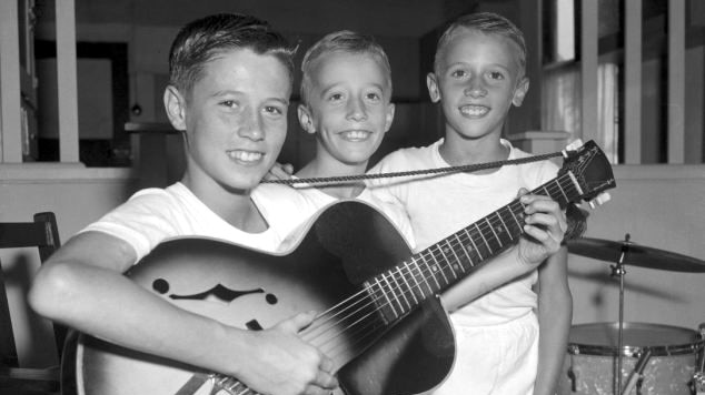 A young Barry, Robin and Maurice Gibb, later know as the Bee Gees, pose with a guitar in Redcliffe, Queensland.