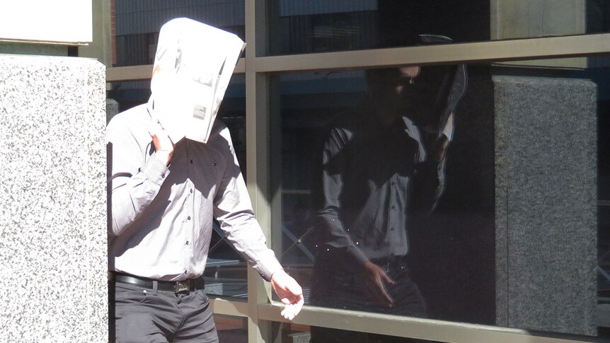Darko Krajinovic hides his faces outside a Hobart court during his trial relating to the demolition of a heritage-listed house.