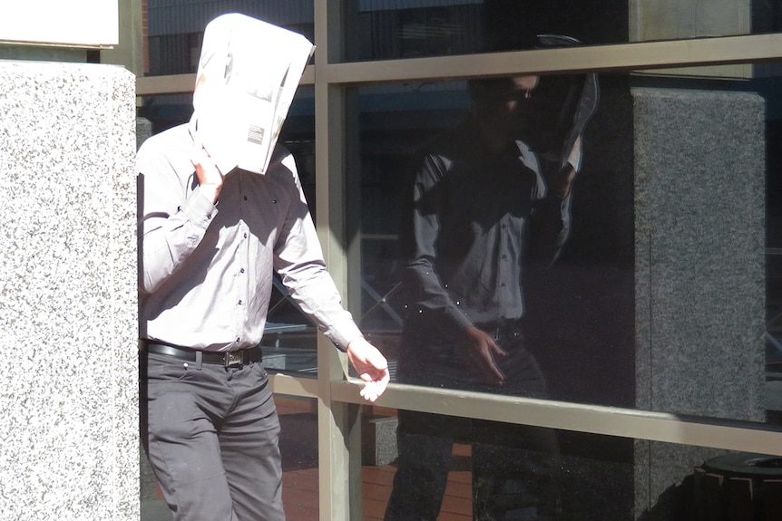 Darko Krajinovic hides his faces outside a Hobart court during his trial relating to the demolition of a heritage-listed house.