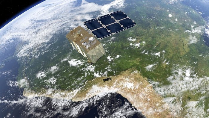 View of satellite in space with its solar panels and the blue planet and green South America below