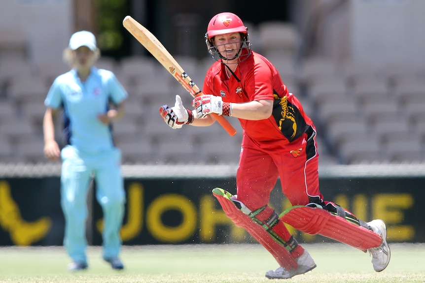 A woman in her South Australian gear with a NSW player fielding behind her