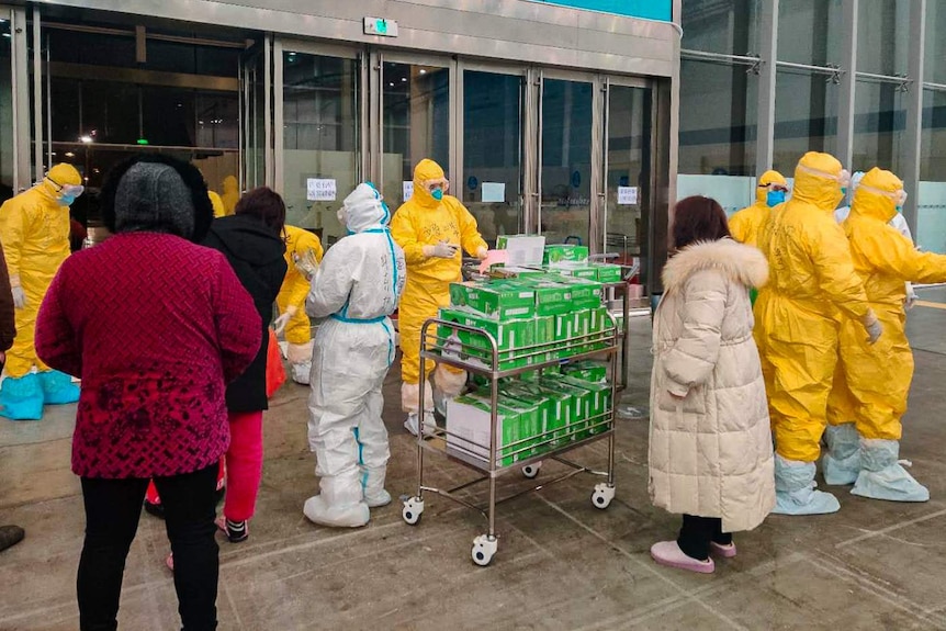 Health workers in protective gear with medical supplies and volunteers pictured in Wuhan.