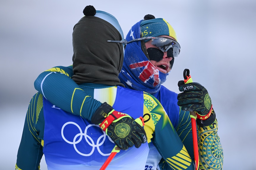 Two Australian male athletes embrace after finishing a cross-country-skiing race at the Beijing Winter Olympics.