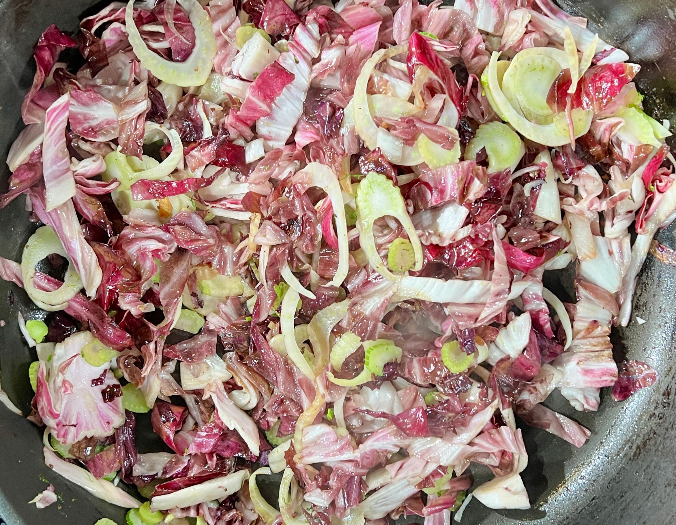 A picture of finely sliced fennel and radicchio sautéing in a pan