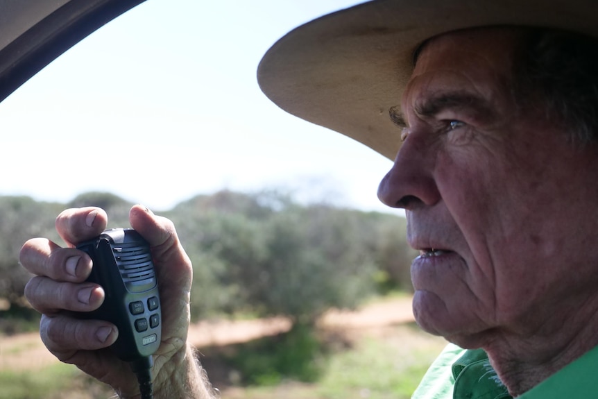 Man in hat holding small radio.