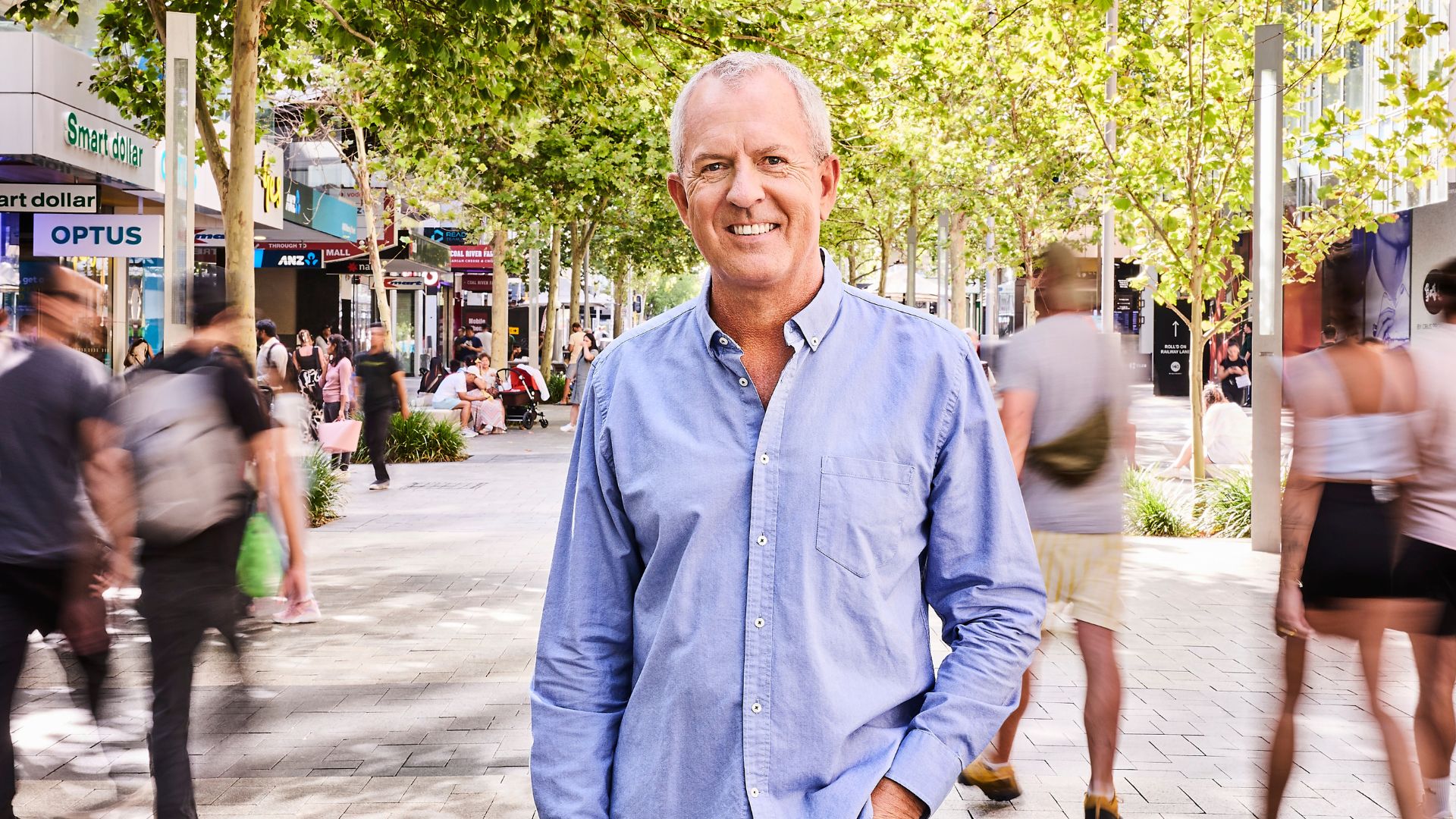 A man stands smiling in a street surrounded by people