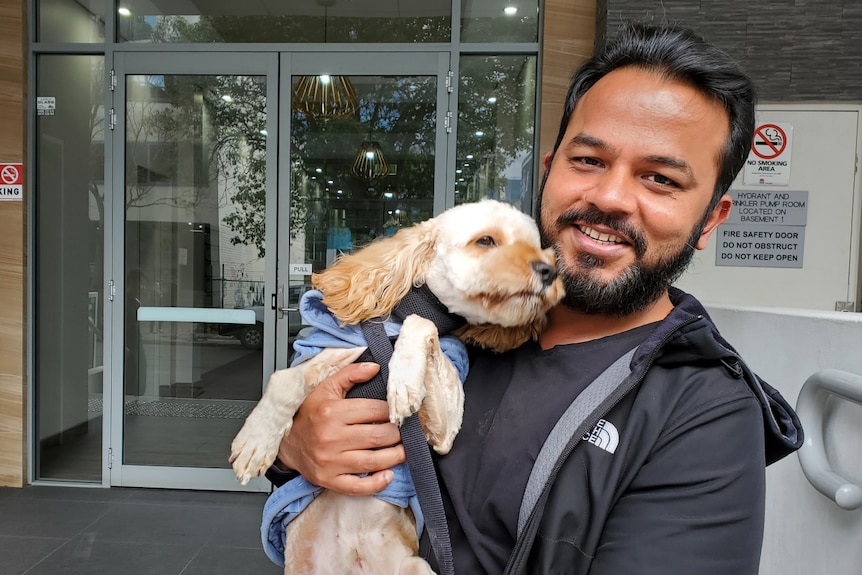 A man smiling at the camera, holding a puppy