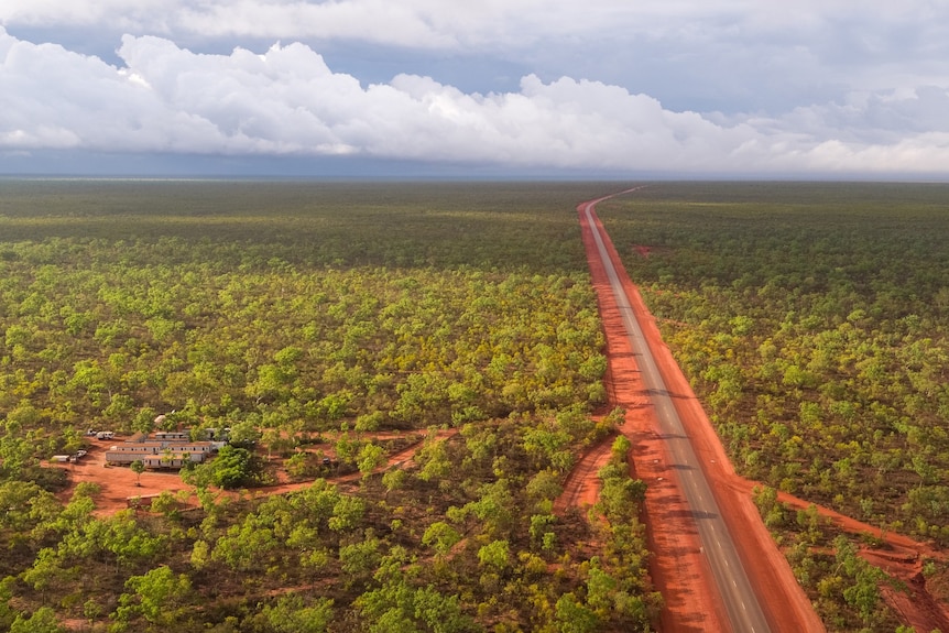 An aerial shot of scrubby vegetation and a long, seal road stretching over the horizon