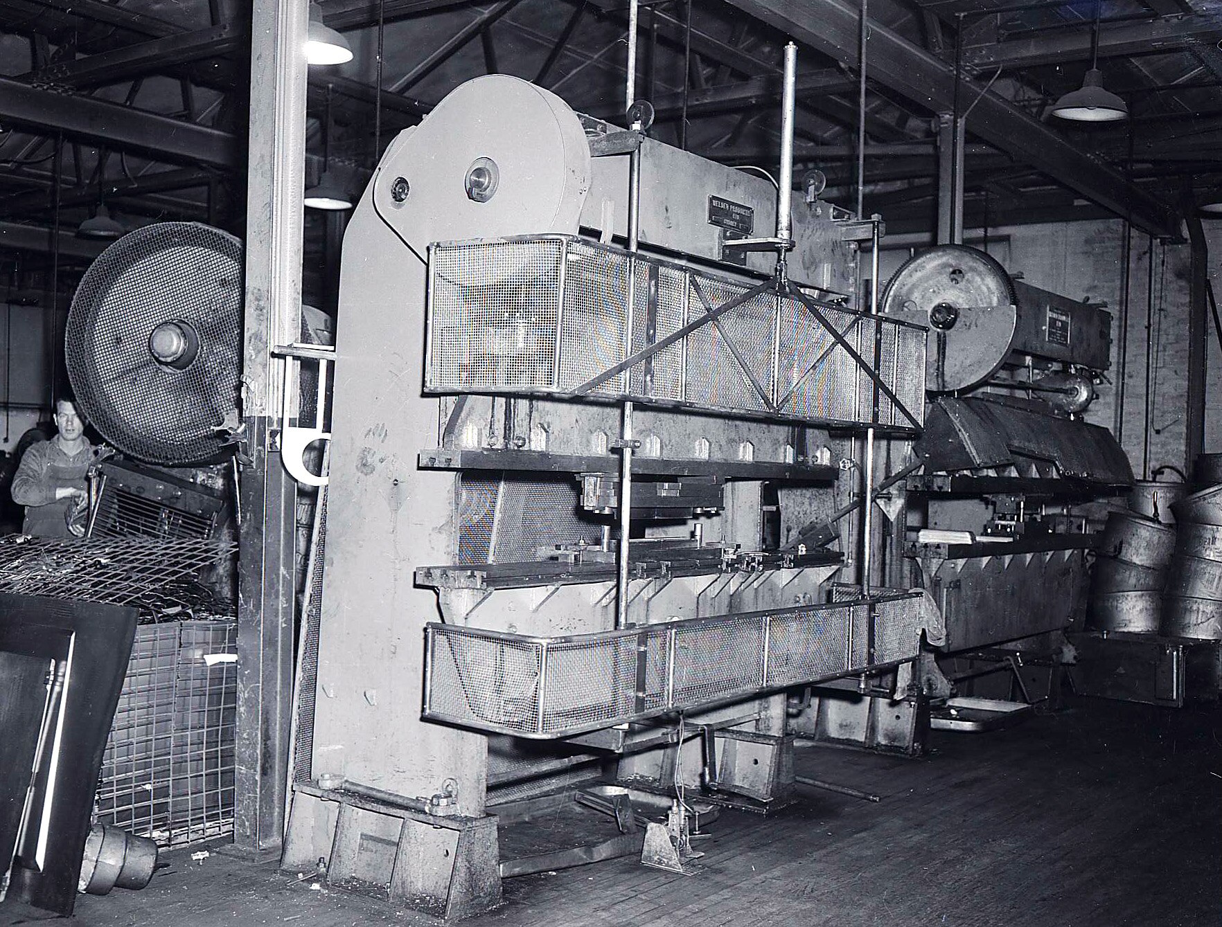 A black and white photograph of a large piece of machinery with a man working on it