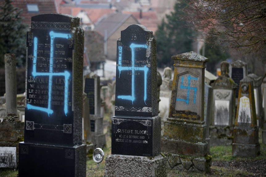 Headstones in a cemetery desecrated with swastikas