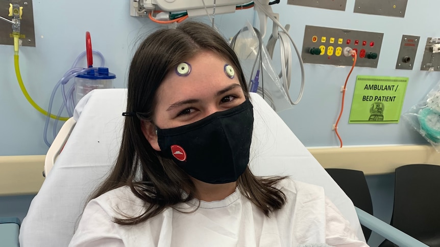 A teenage girl wearing a face mask in hospital