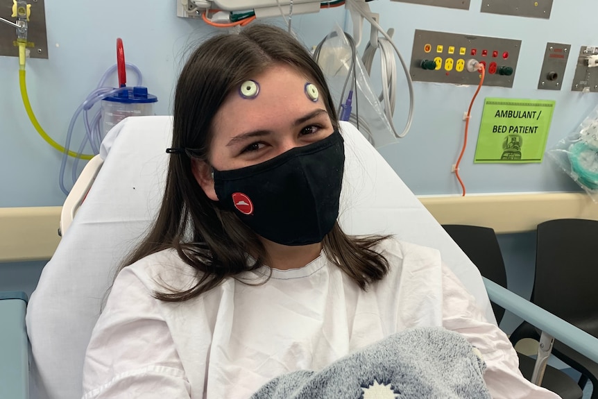 A teenage girl wearing a face mask in hospital