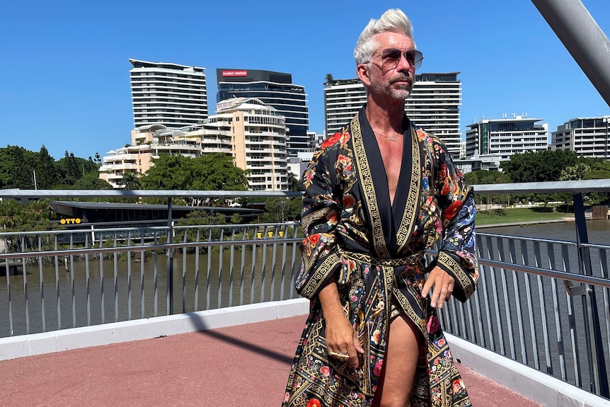 Grey-haired man in sunglasses wearing patterned dressing gown and snake skin boots