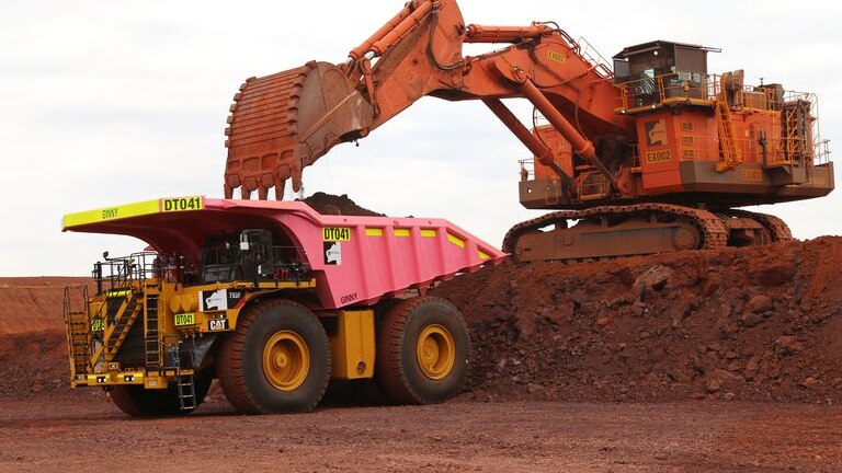 An excavator loading a pink iron ore truck in the Pilbara.