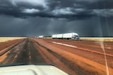 a dark, cloudy sky with a bogged truck on the side of the road