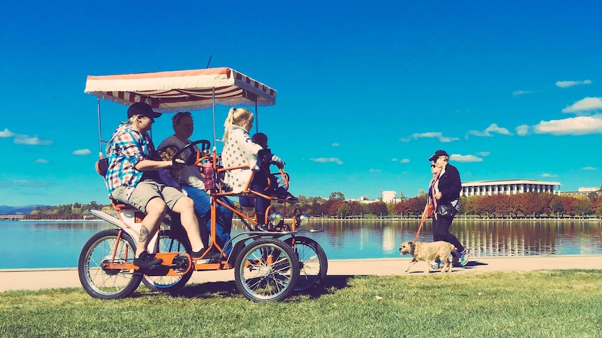 A family rides a kitsch bike around Canberra's Lake Burley Griffin.