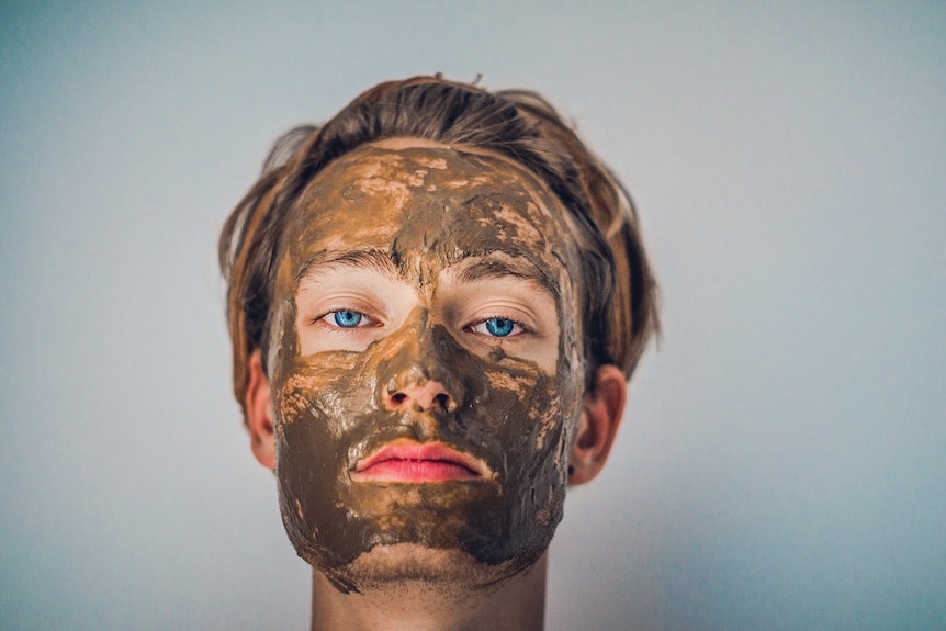 A mud mask on the face of a person staring straight at a camera