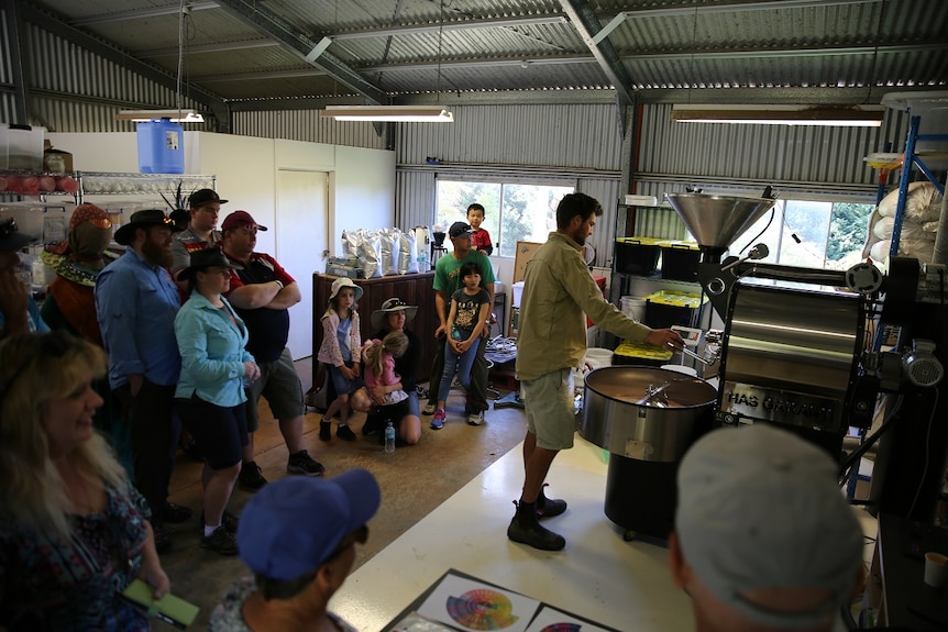 Consumers watch coffee roaster Liam Smith demonstrate the roasting of the beans.