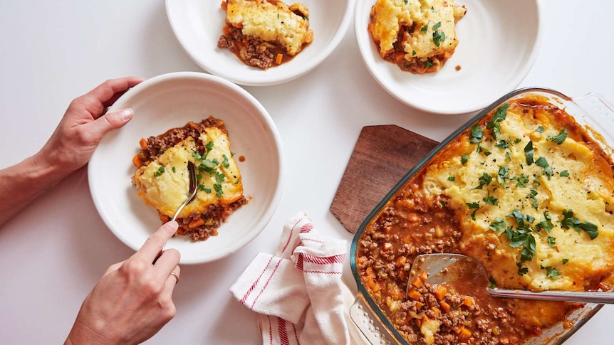 Three bowls of beef cottage pie alongside a tray of the finished meal, comfort food for the cooler seasons.