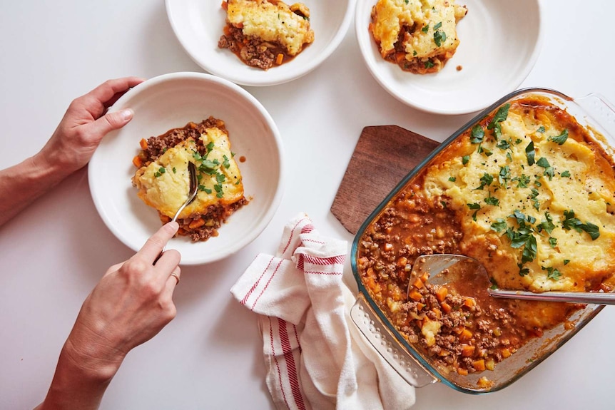 Three bowls of beef cottage pie alongside a tray of the finished meal, comfort food for the cooler seasons.