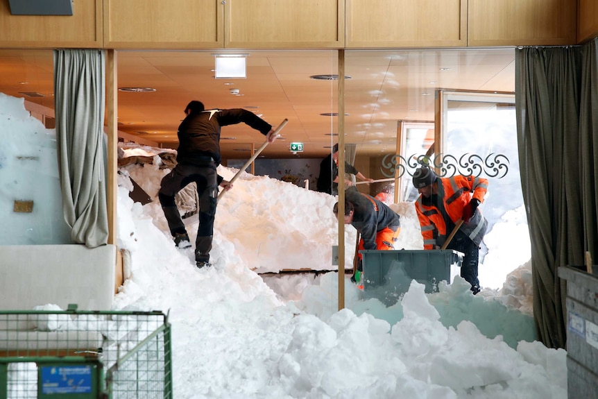 Workers shovel snow out of a restaurant