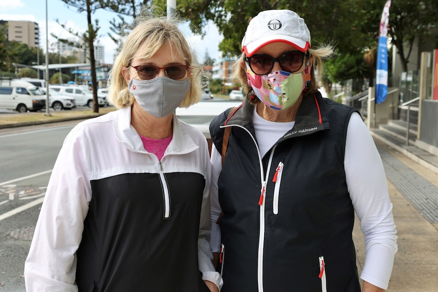 Local residents and friends Liz Knowles and Julie Fox stand in a street on Queensland's Gold Coast wearing face masks