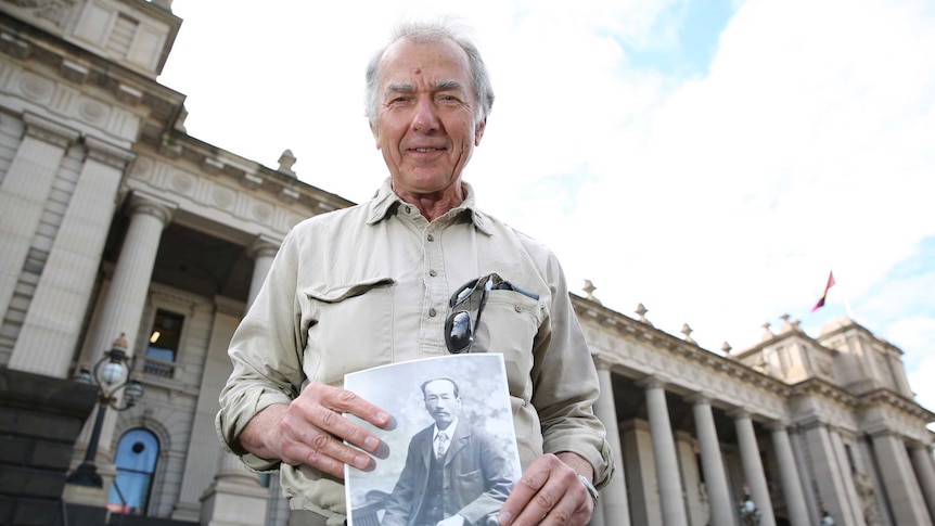 Max Brady holds a photo of Wong Ah Sat outside Parliament House