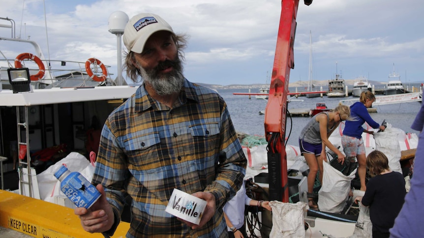 Matt Dell holds up foreign rubbish washed up on Tasmanian beaches